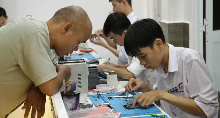 nhân viên 24h đang sửa chữa điện thoại cho khách hàng